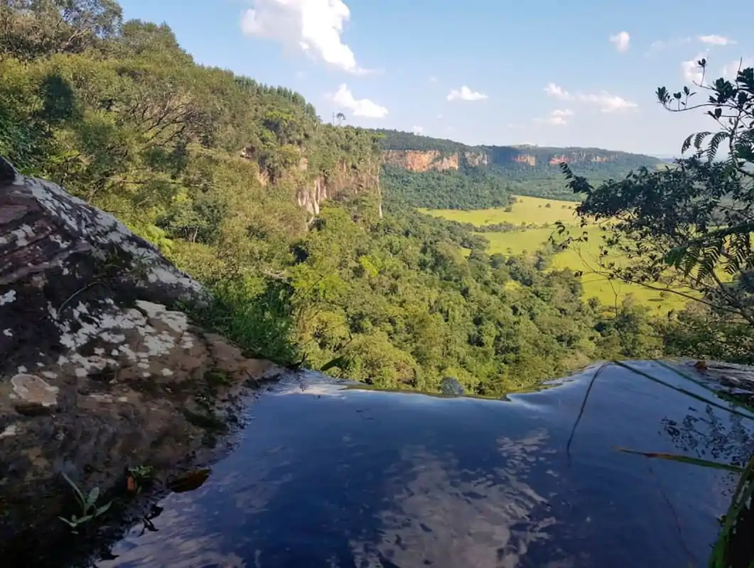 Cachoeira da Bocaina em Analândia (SP), vista do topo da queda com a lâmina d'água, o vale verde e os paredões de arenito ao fundo